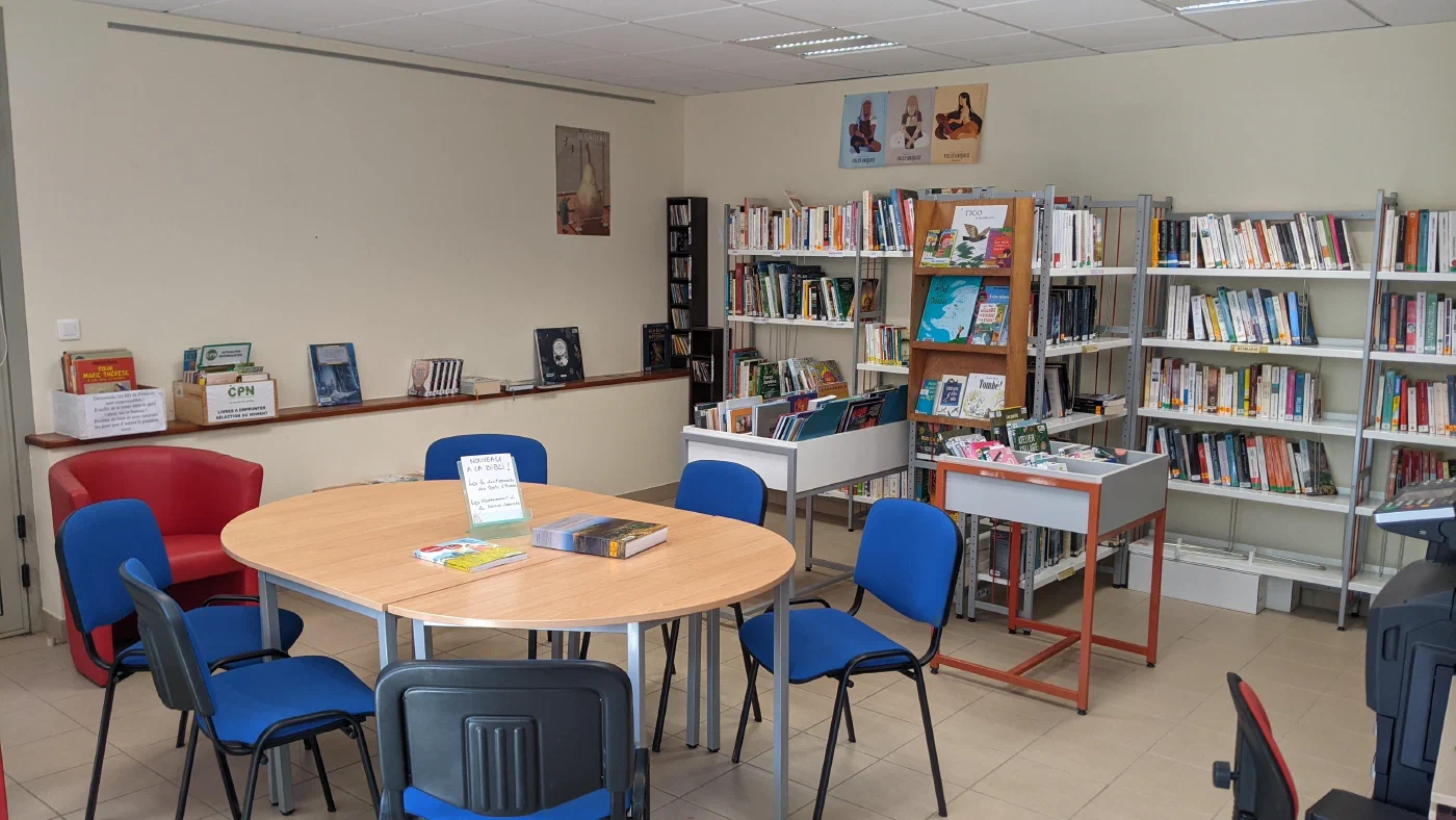 L'espace adultes de la bibliothèque, avec ses rayonnages, sa table ronde et son coin lecture